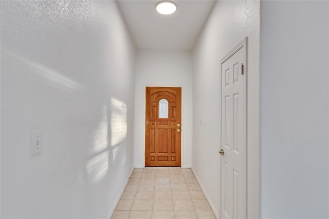 doorway to outside with light tile patterned flooring and baseboards