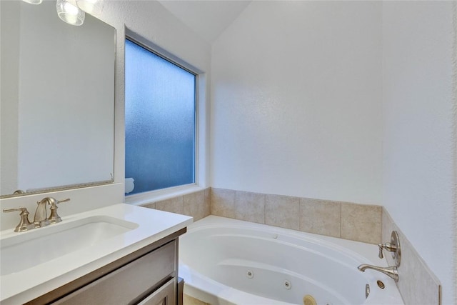 bathroom with vaulted ceiling, a jetted tub, and vanity