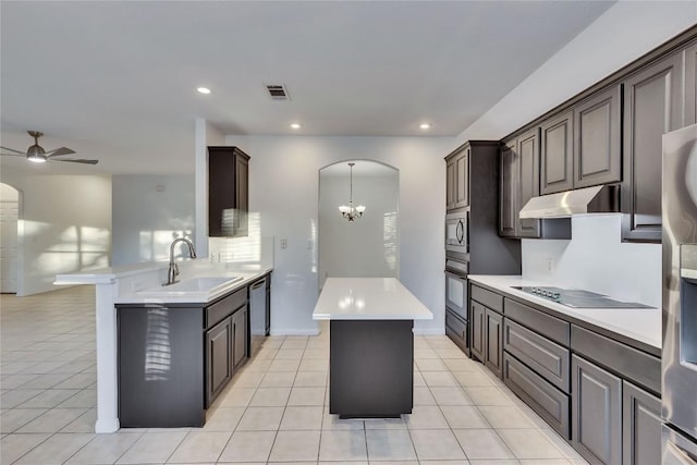 kitchen with visible vents, arched walkways, under cabinet range hood, black appliances, and a sink