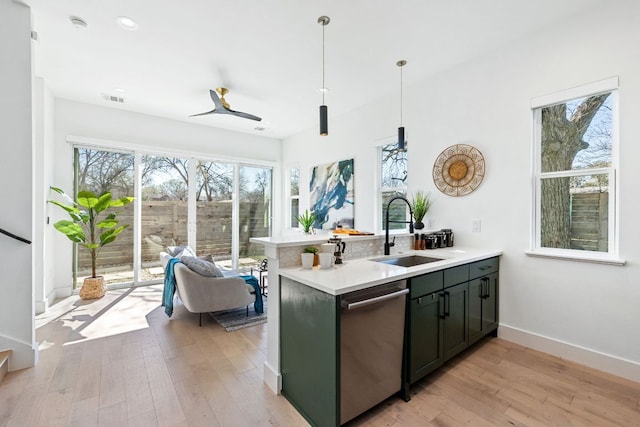 kitchen with light wood-style flooring, a sink, visible vents, light countertops, and stainless steel dishwasher