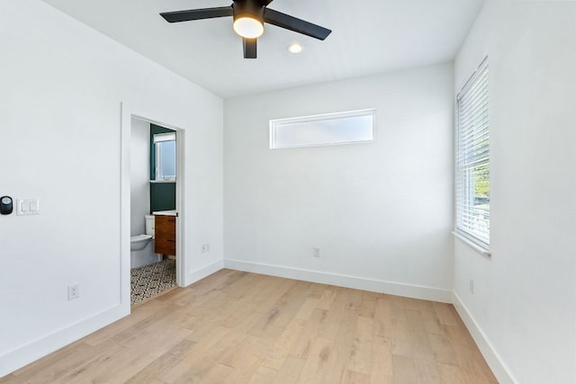 unfurnished bedroom with light wood-style floors, ceiling fan, baseboards, and connected bathroom