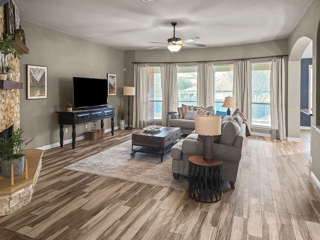 living room with plenty of natural light, a fireplace, arched walkways, and wood finished floors