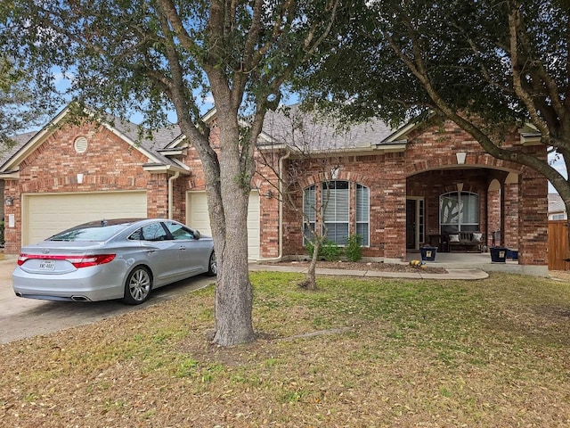 view of front of house featuring a front yard, brick siding, driveway, and an attached garage