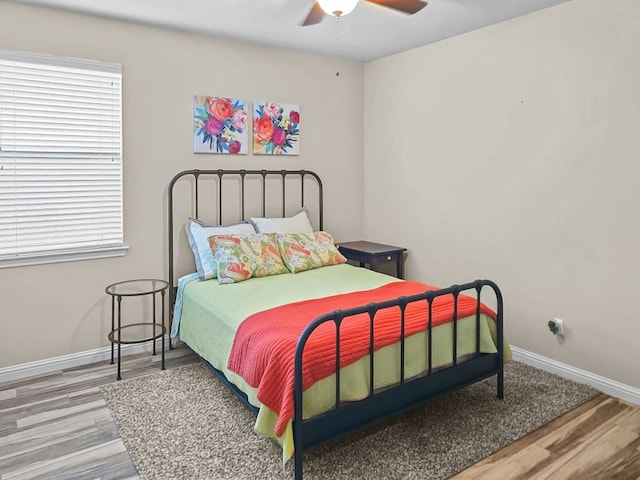 bedroom with wood finished floors, a ceiling fan, and baseboards