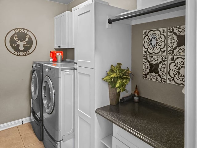 laundry area featuring light tile patterned floors, washing machine and dryer, cabinet space, and baseboards