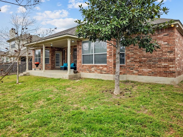 rear view of house featuring a patio, fence, a lawn, and brick siding