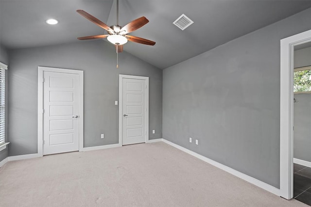 unfurnished bedroom with baseboards, visible vents, lofted ceiling, ceiling fan, and carpet