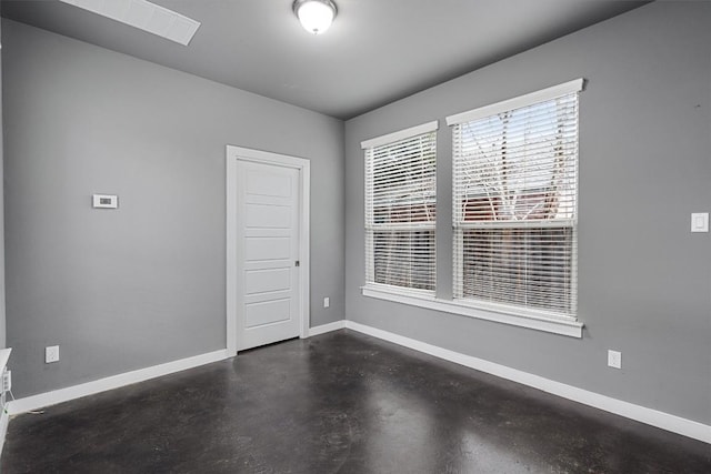 unfurnished room featuring concrete floors and baseboards