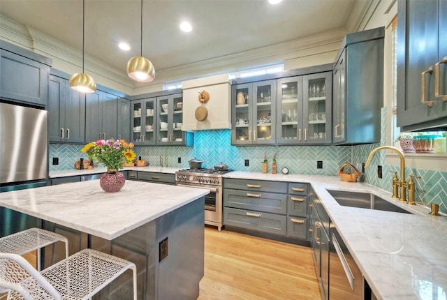 kitchen with hanging light fixtures, appliances with stainless steel finishes, a sink, light stone countertops, and a kitchen bar