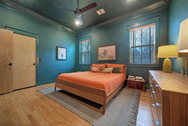 bedroom featuring light wood finished floors, multiple windows, visible vents, and ornamental molding