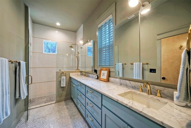 bathroom with double vanity, tile patterned flooring, a sink, and tiled shower