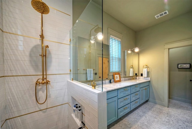 full bathroom featuring baseboards, visible vents, a tile shower, and vanity