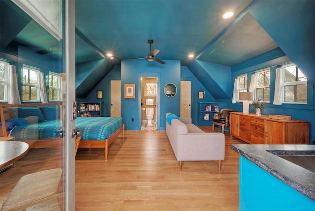 bedroom with light wood-style floors, multiple windows, and vaulted ceiling