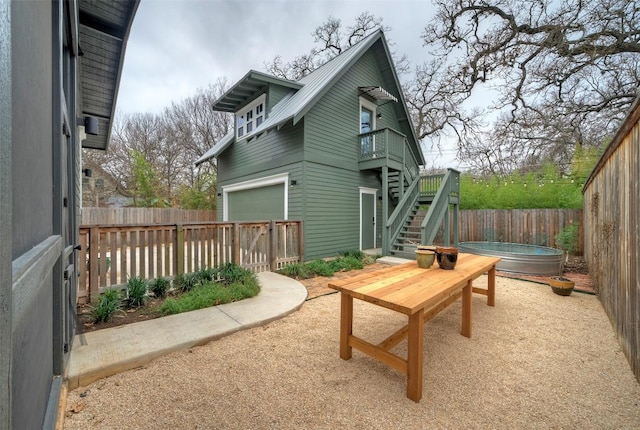 rear view of property featuring a hot tub, a patio, a fenced backyard, metal roof, and stairs