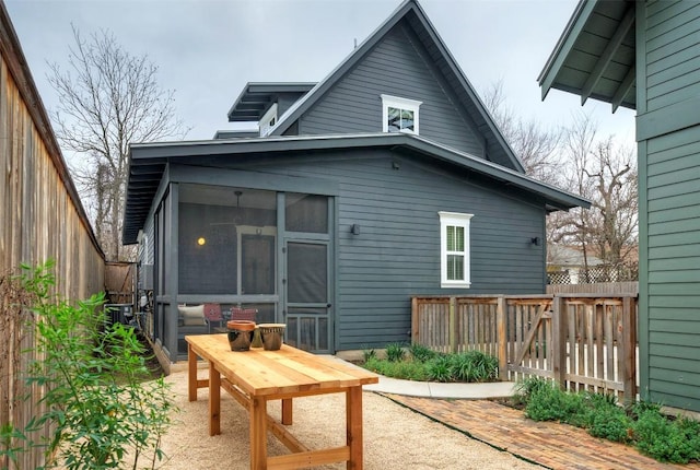 rear view of property with a sunroom, a patio area, and fence