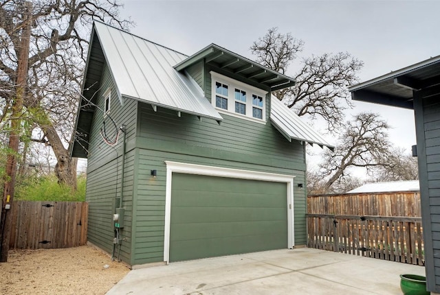 view of side of property with metal roof, fence, and driveway