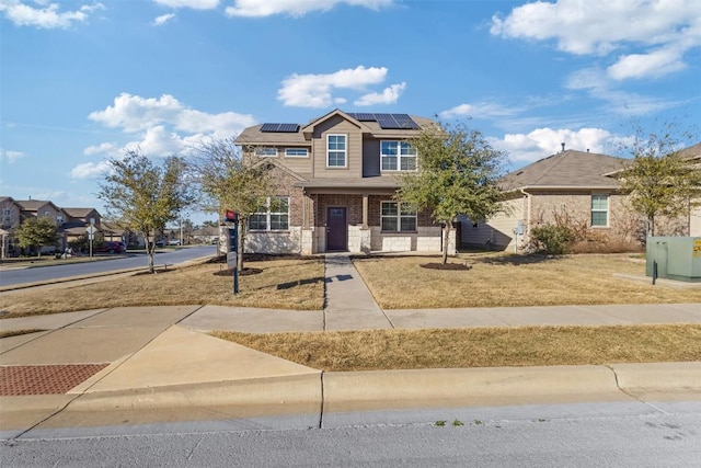 view of front of house with covered porch, a front yard, and roof mounted solar panels