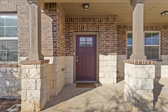 entrance to property with a porch and brick siding