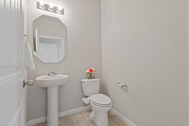 bathroom featuring toilet, tile patterned flooring, baseboards, and a sink