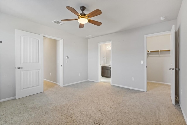 unfurnished bedroom with baseboards, carpet flooring, visible vents, and a walk in closet