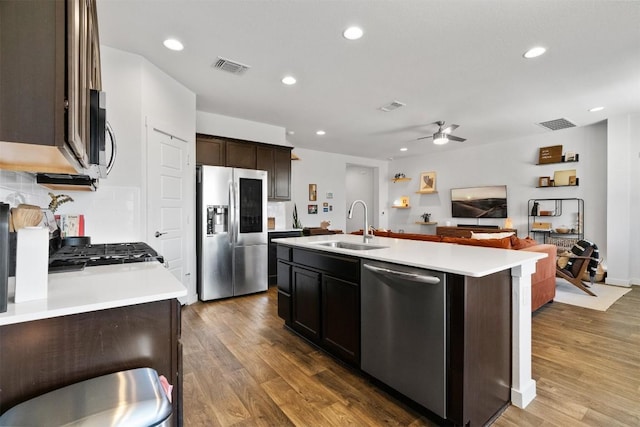 kitchen featuring visible vents, open floor plan, wood finished floors, stainless steel appliances, and a sink