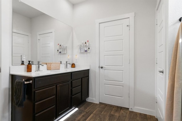 bathroom featuring double vanity, a sink, baseboards, and wood finished floors