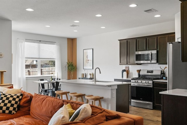 kitchen featuring wood finished floors, a sink, visible vents, light countertops, and appliances with stainless steel finishes