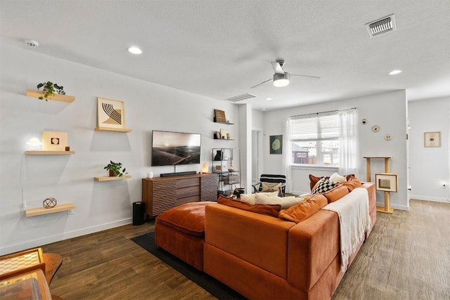 living room with a ceiling fan, visible vents, baseboards, and wood finished floors