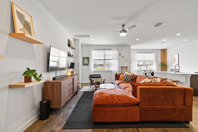 living room with baseboards, visible vents, wood finished floors, and recessed lighting