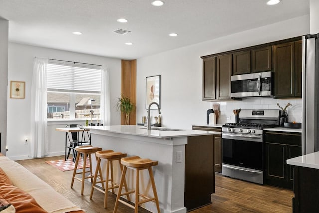 kitchen with stainless steel appliances, dark wood-style flooring, a sink, visible vents, and light countertops