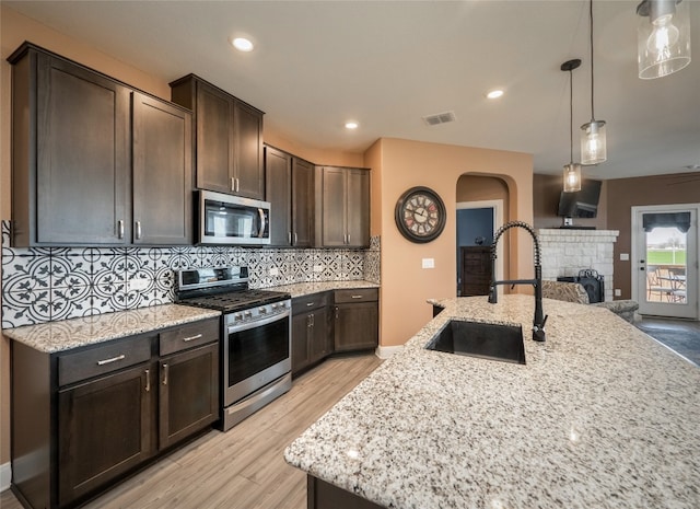 kitchen featuring stainless steel appliances, visible vents, decorative backsplash, dark brown cabinetry, and a sink