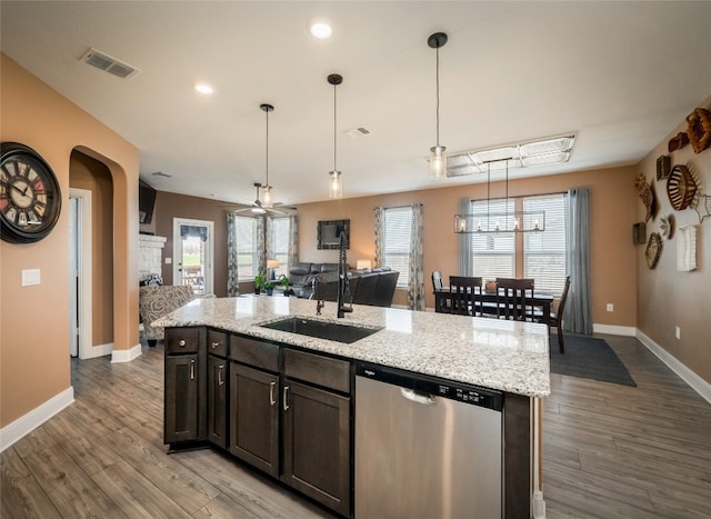 kitchen with visible vents, dishwasher, open floor plan, a stone fireplace, and a sink