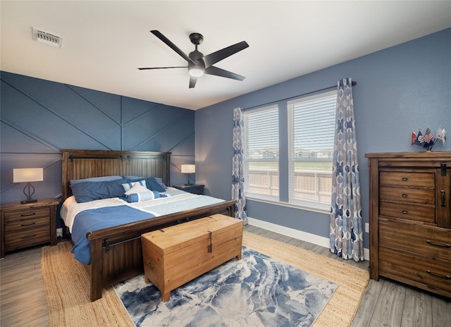 bedroom featuring a ceiling fan, light wood-type flooring, visible vents, and baseboards