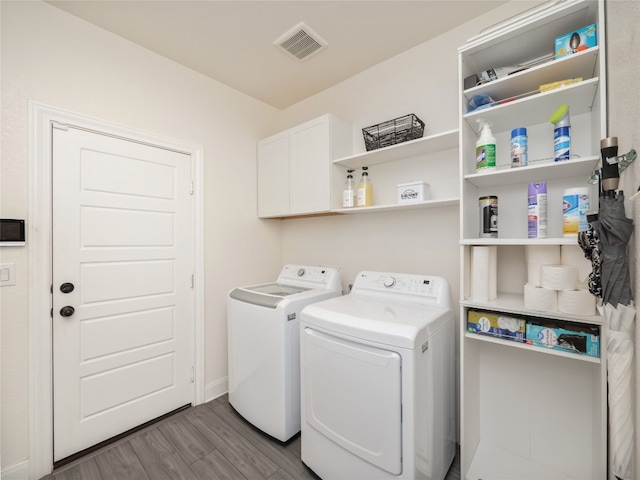 clothes washing area featuring wood finished floors, visible vents, baseboards, independent washer and dryer, and cabinet space