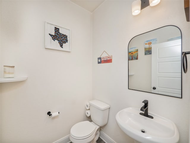 bathroom with baseboards, a sink, and toilet