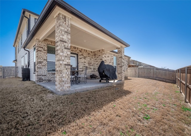 rear view of property with a patio area, a fenced backyard, and a lawn