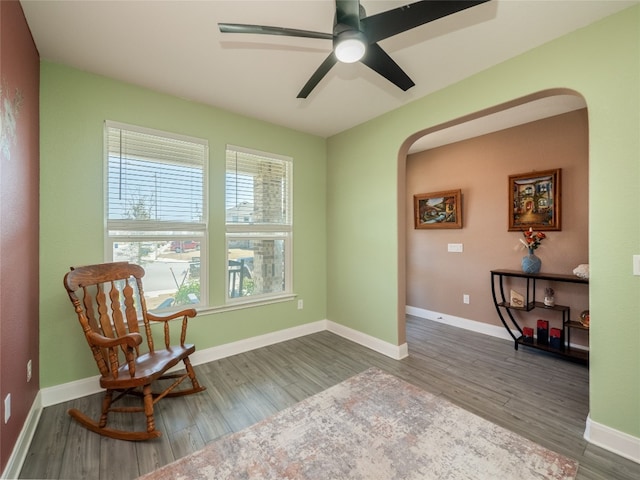 living area featuring arched walkways, wood finished floors, and baseboards