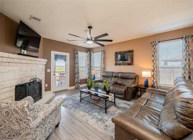 living area with a wealth of natural light, a fireplace, wood finished floors, and visible vents