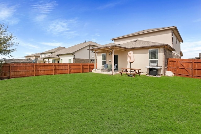 rear view of house featuring stucco siding, a fenced backyard, a patio area, and a yard