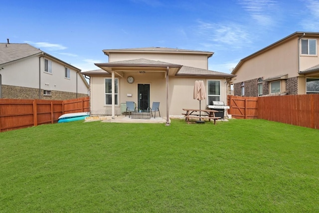 rear view of property featuring a patio area, a fenced backyard, a lawn, and stucco siding