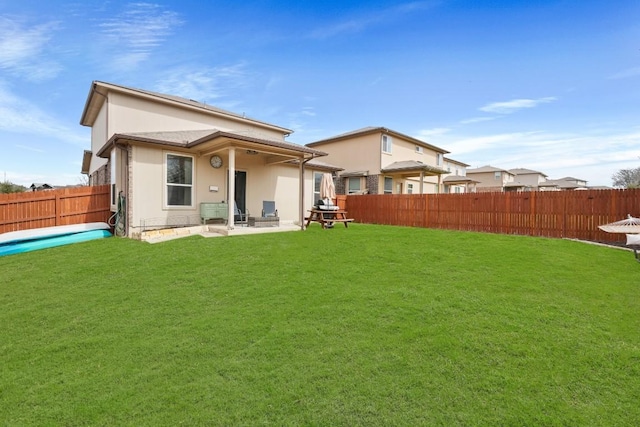 back of house featuring a fenced backyard, a lawn, and stucco siding