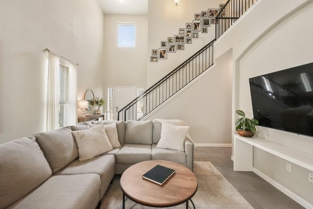 tiled living area with a high ceiling, stairway, and baseboards