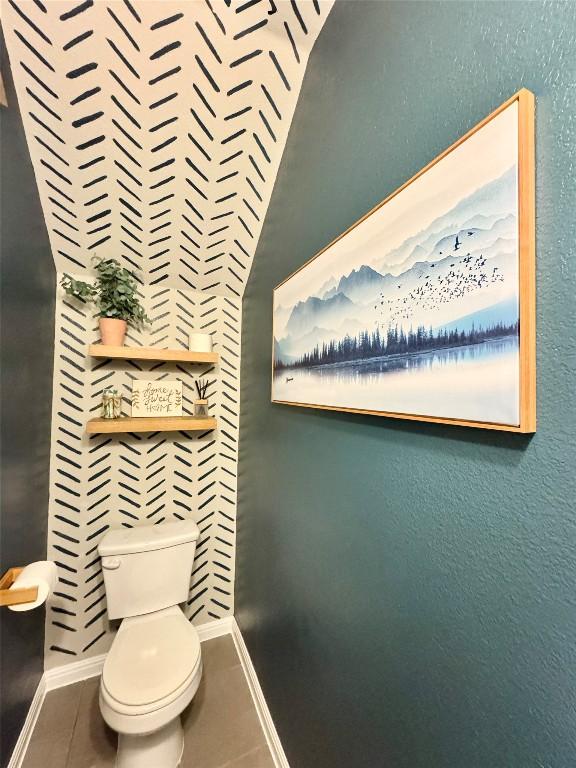 bathroom featuring tile patterned flooring, baseboards, and toilet