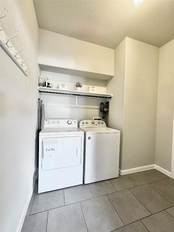 washroom with a textured ceiling, tile patterned flooring, laundry area, independent washer and dryer, and baseboards