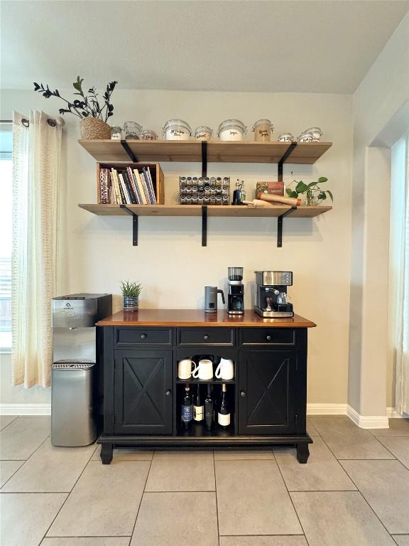 bar featuring light tile patterned floors, a healthy amount of sunlight, and baseboards