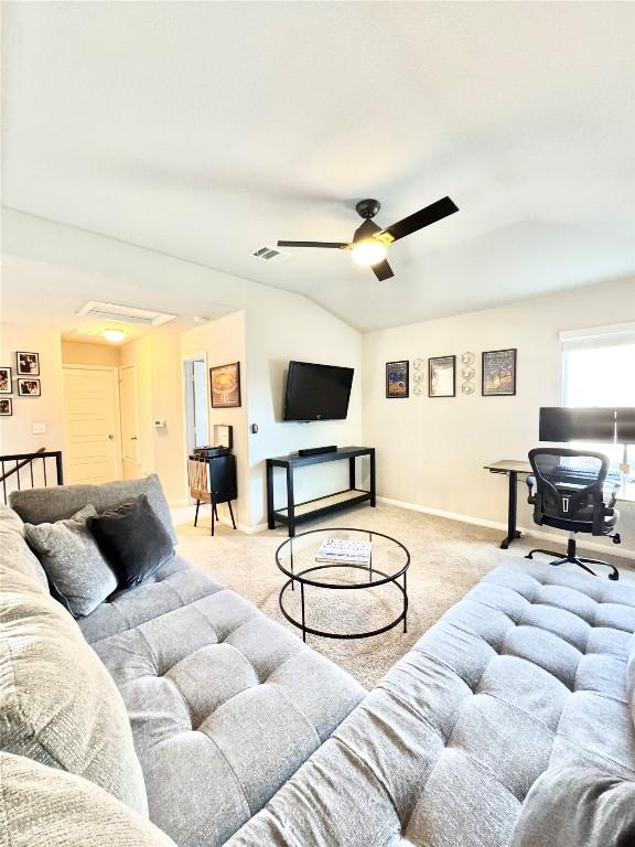 living area with baseboards, visible vents, light colored carpet, lofted ceiling, and ceiling fan