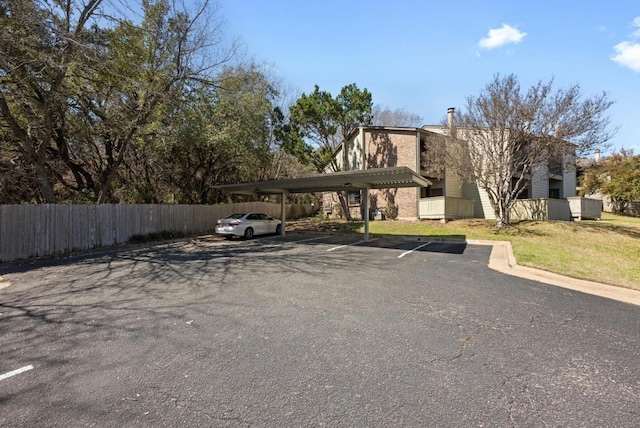 partially covered parking lot featuring fence