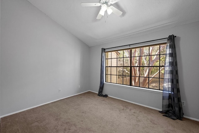 carpeted spare room featuring lofted ceiling, a textured ceiling, baseboards, and a ceiling fan