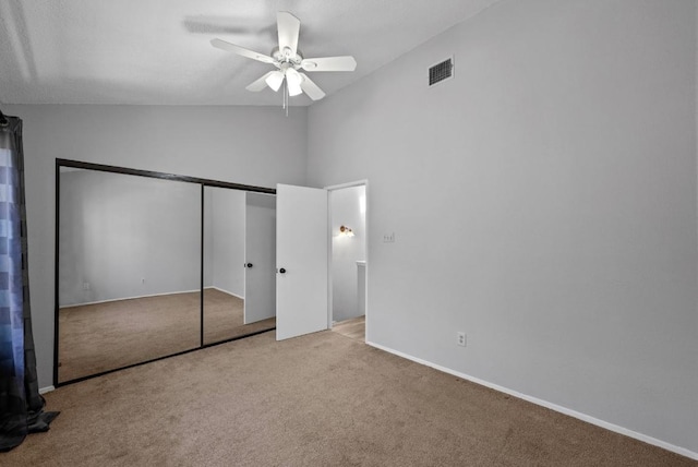 unfurnished bedroom with a closet, visible vents, a ceiling fan, carpet flooring, and vaulted ceiling