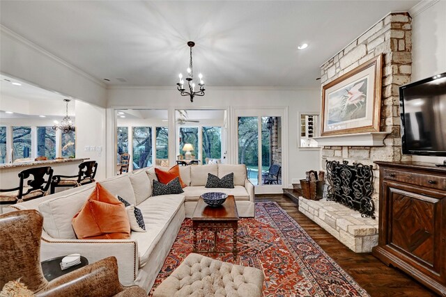 living area featuring recessed lighting, dark wood-style flooring, a chandelier, crown molding, and a stone fireplace